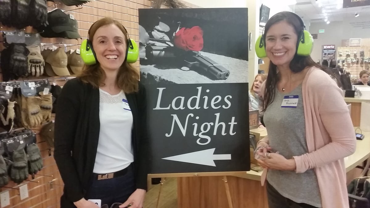 Betz stands and smiles next to sign reading "ladies night" with her coworker