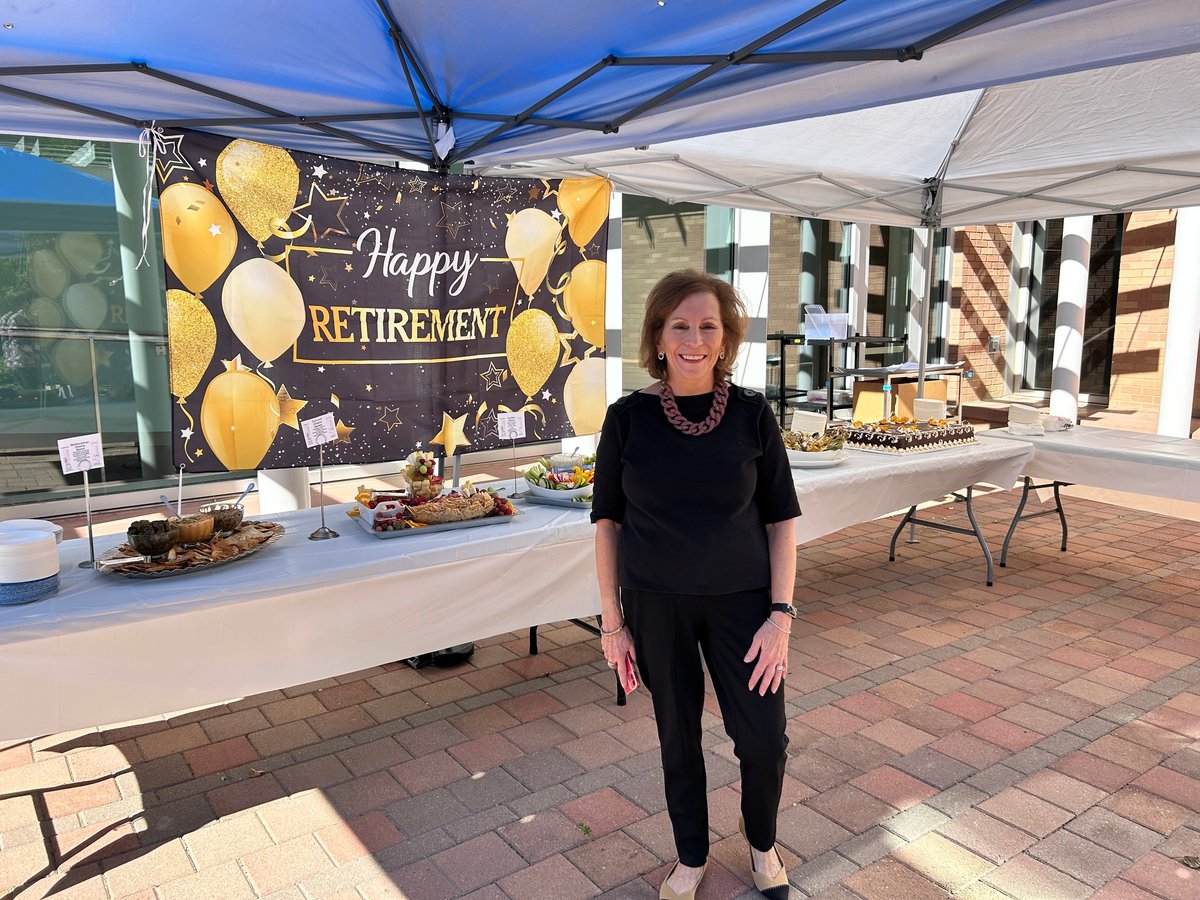 Terri Tilliss in front of Happy Retirement banner and table with food and cake