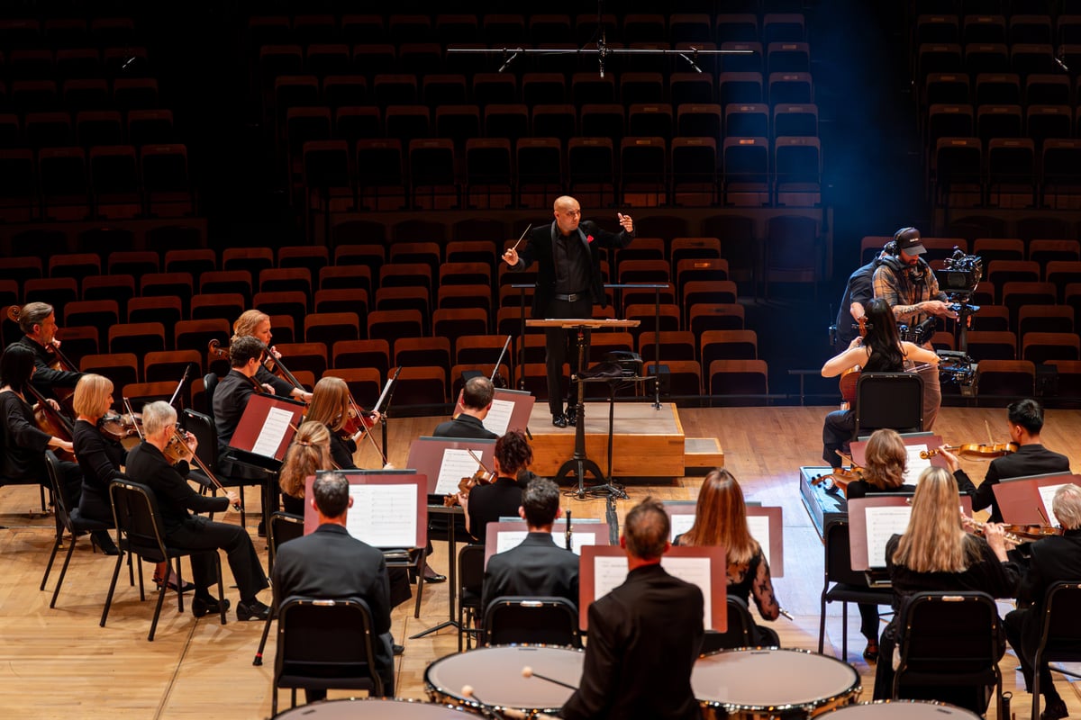 Assembled members of the Colorado Symphony play under the direction of their conductor.
