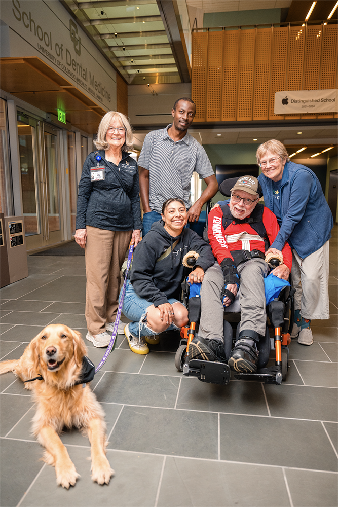group of people, one in wheelchair, with dog in front